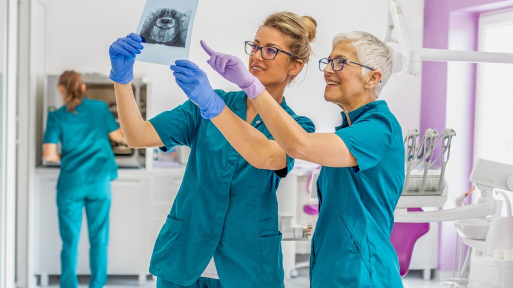 A dentist and a dental technician review X-rays in a dental office.