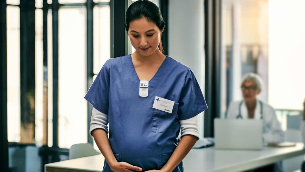 Pregnant healthcare worker wearing NetDose in scrubs.
